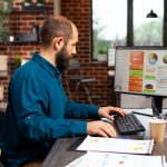 Entrepreneur man sitting at desk table typing management strategy on computer