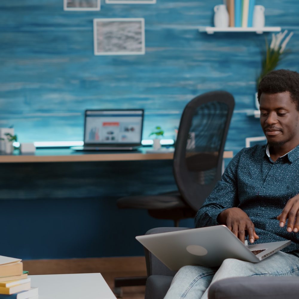 African american man browsing using laptop computer, searching social media